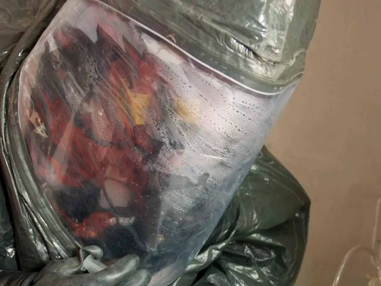 Here in this picture we can see a person wearing a lab suit with helmet and gloves on him and he is...