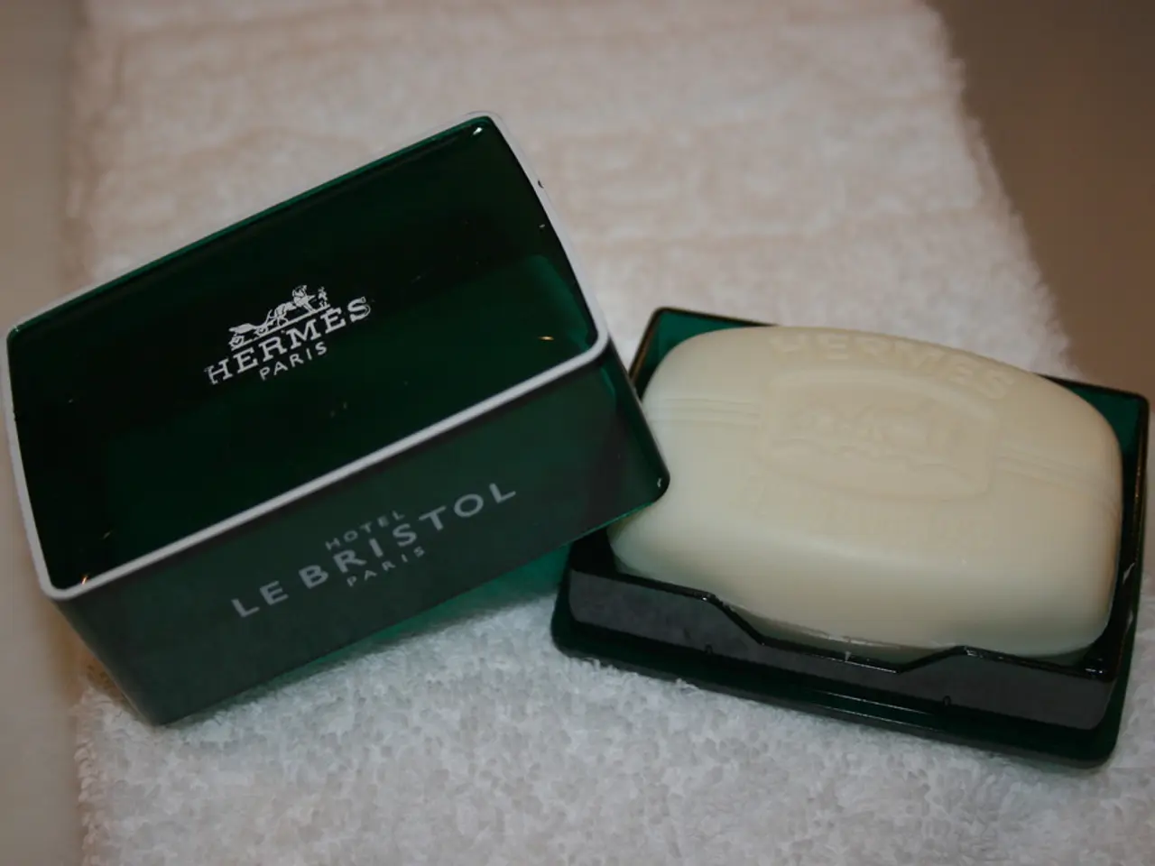 In the image there on the cloth there is a box with a soap. Beside that there is a box lid with...