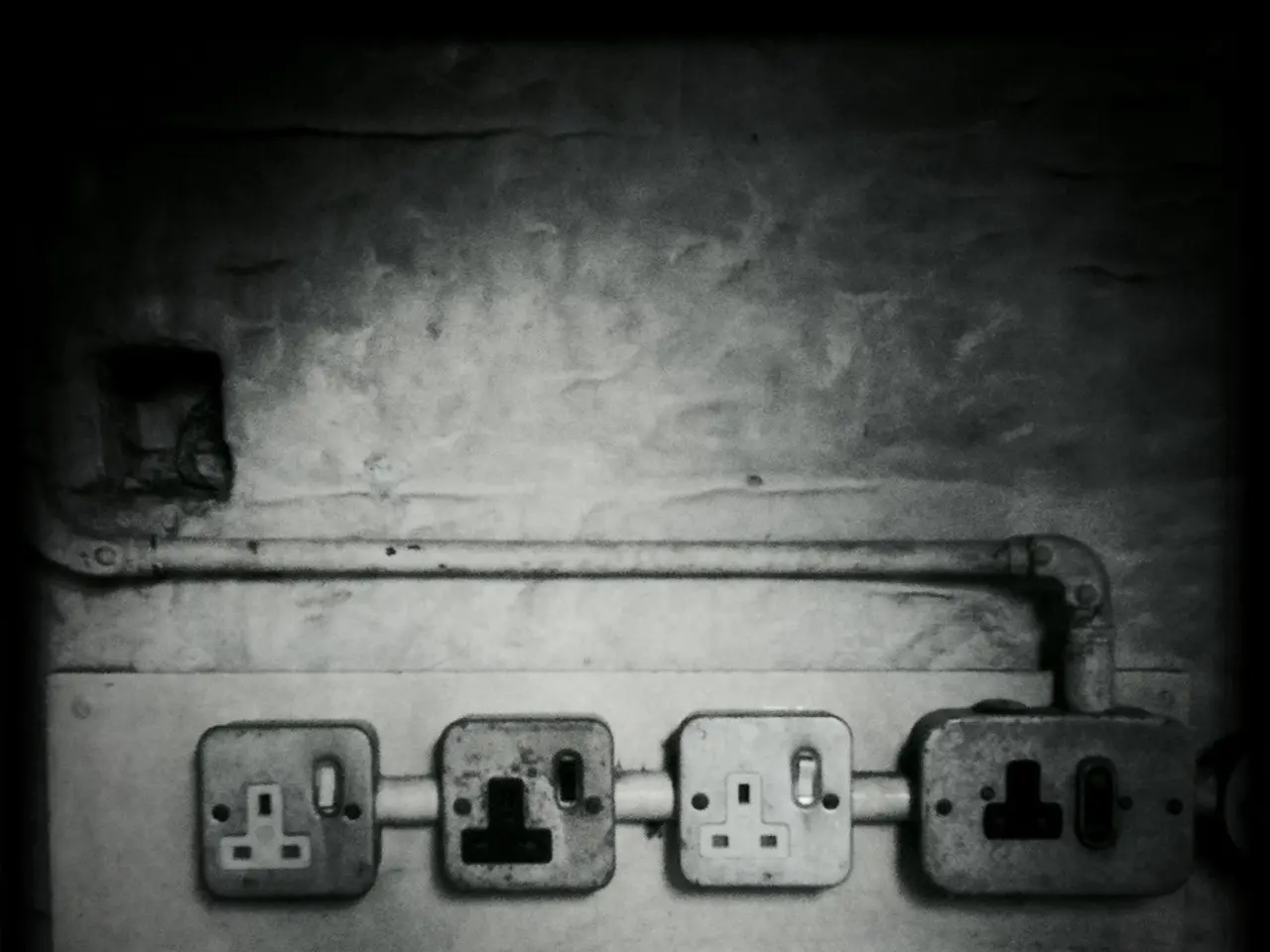 In this picture I can see the sockets and a pipe on the wall. I see that this is a black and white...
