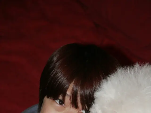 In this image a woman is smiling and holding a pet in her arms.