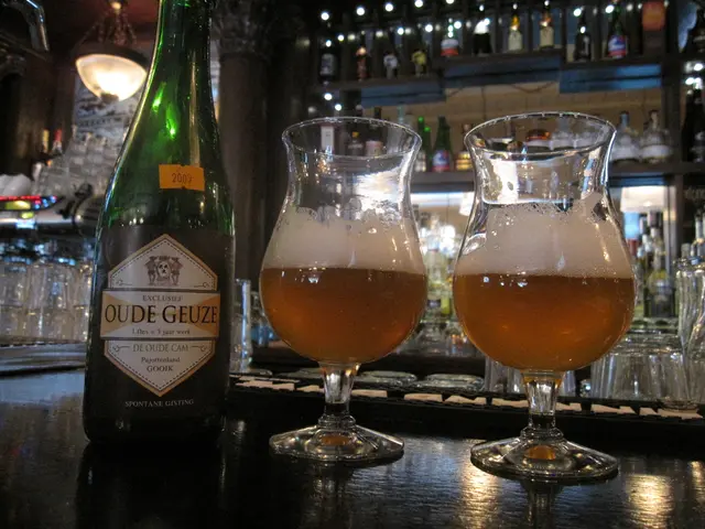 There is a bottle, two wine glasses are on the table. There is a logo on the bottle. In the...